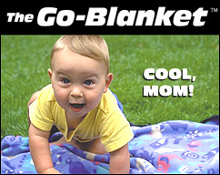 A happy toddler playing on his Go-Blanket in a green, grassy park.